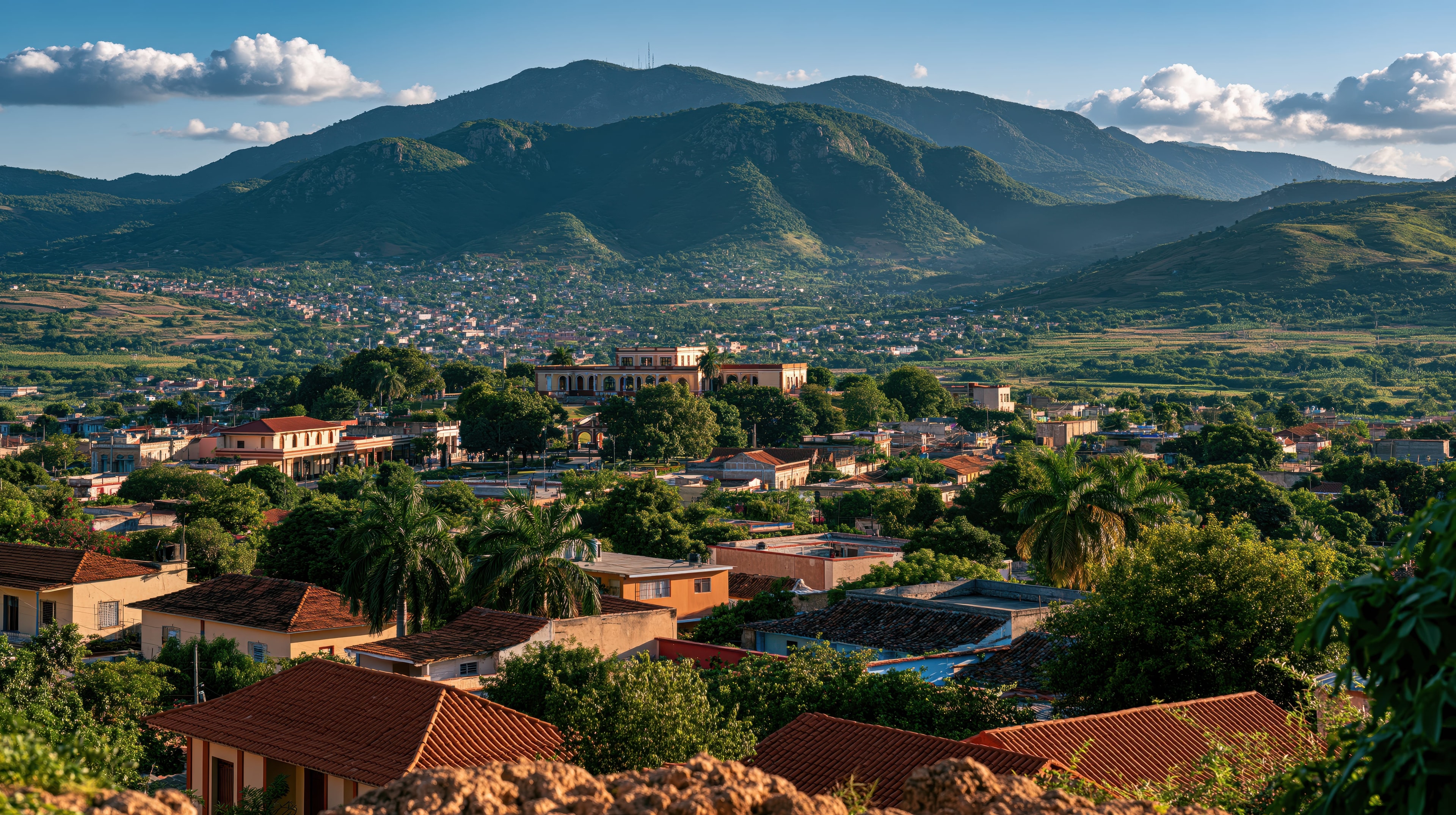 Trinidad Cuba rooftop panorama with terracotta tiles, lush tropical trees, and Escambray mountain range at golden hour
