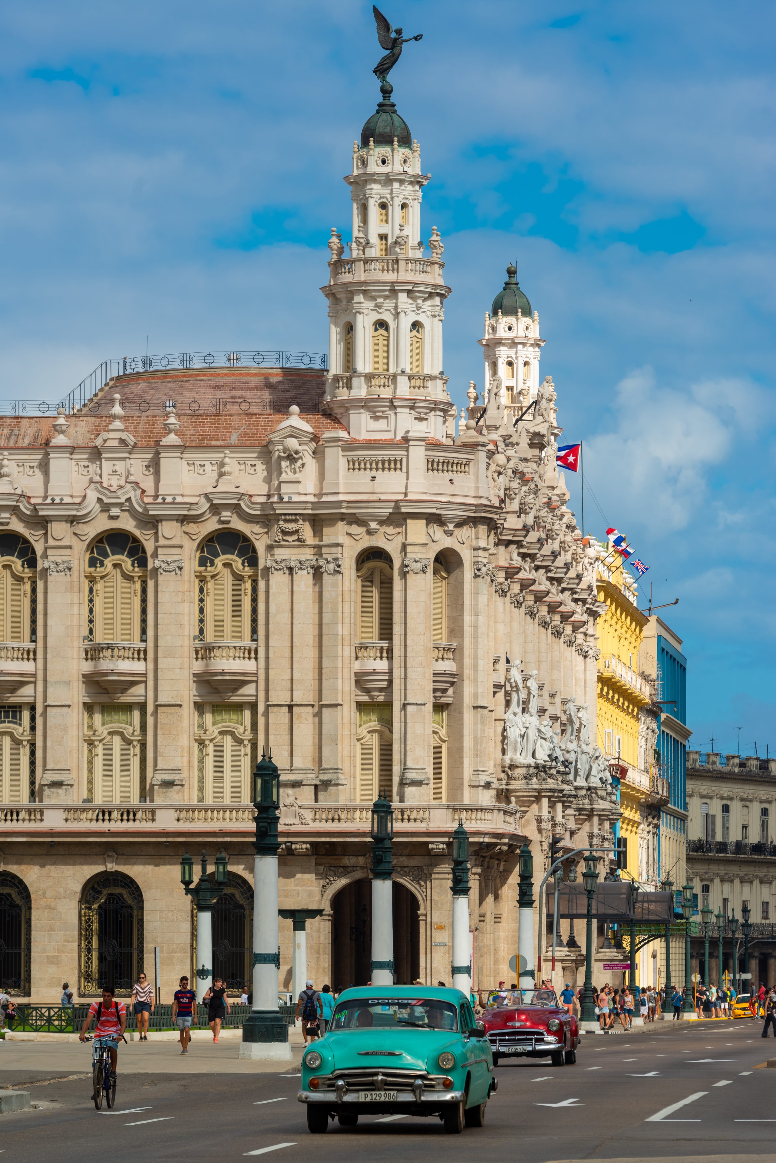 Gran Teatro de La Habana baroque facade with angel statue, ornate towers, and teal vintage Dodge on street, Cuba