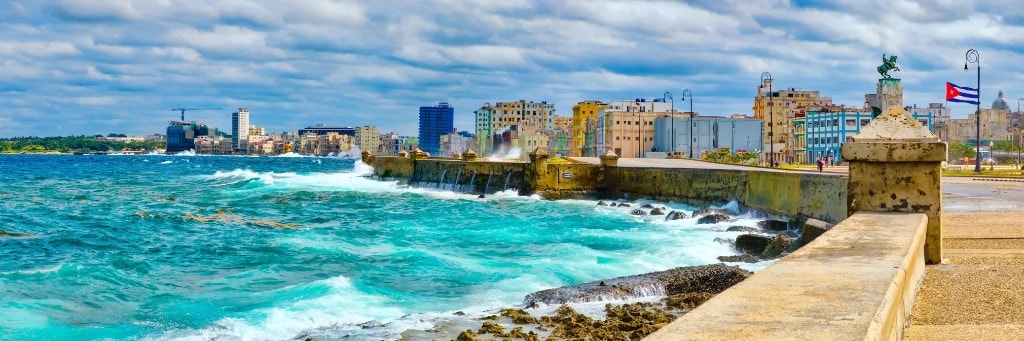 Malecon seawall Havana with crashing waves and Cuban flag