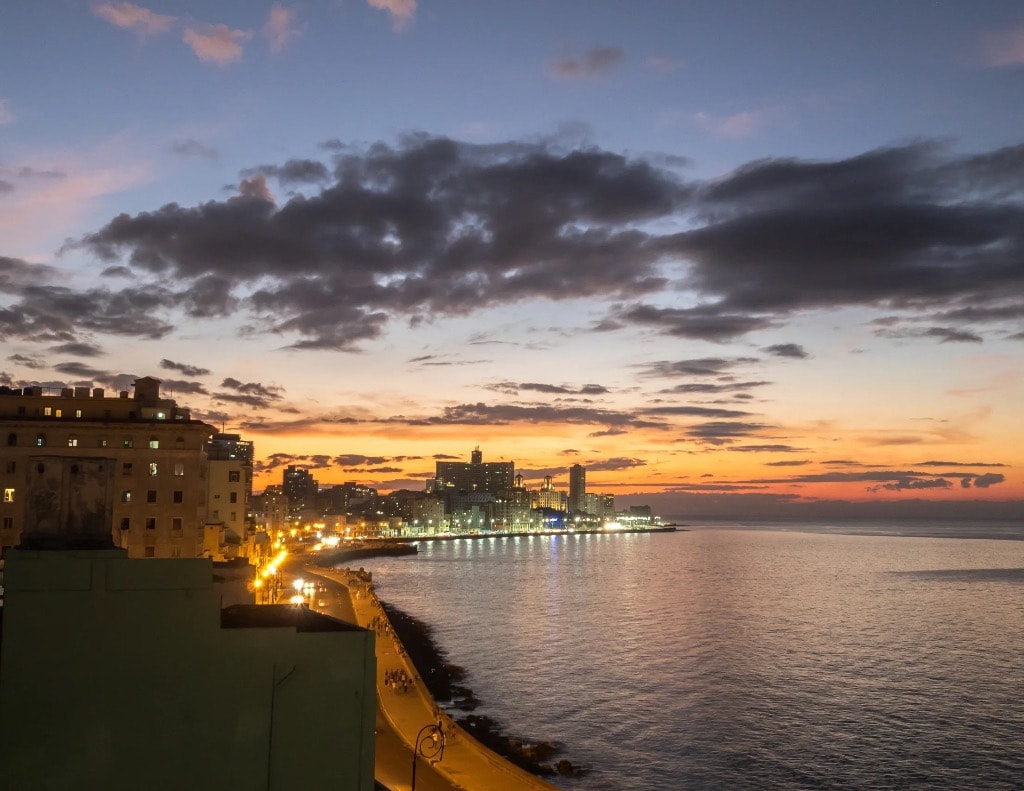 Havana Malecón seawall at twilight with city lights and calm sea