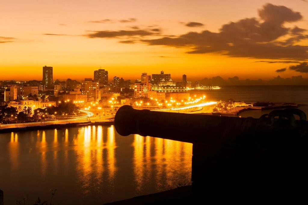Havana skyline at golden sunset with cannon silhouette in foreground Cuba