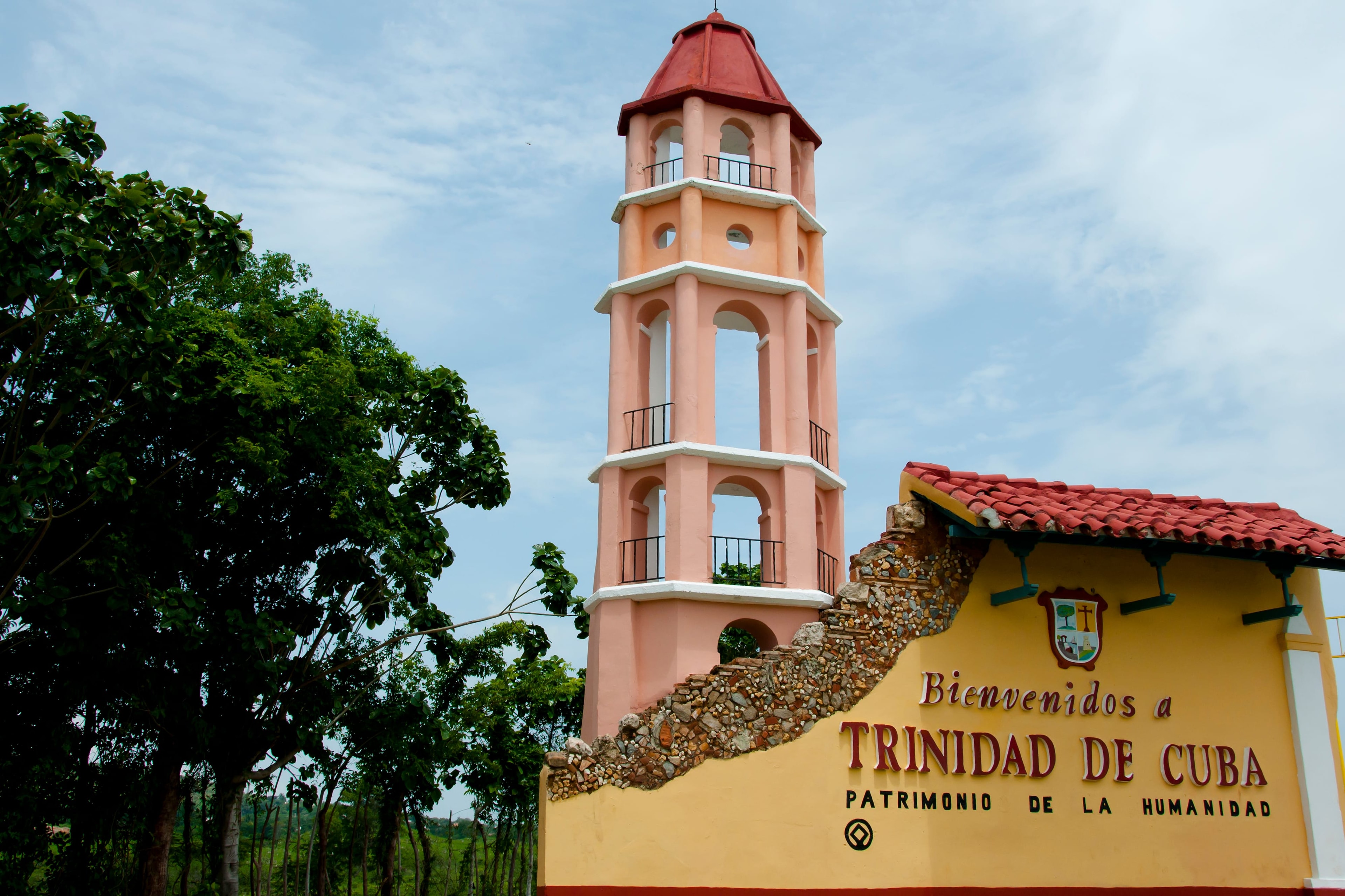 Trinidad de Cuba welcome sign with iconic pink bell tower and lush tropical trees, UNESCO World Heritage Site
